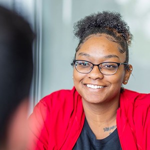 Woman in red shirt with glasses smiling at dentist