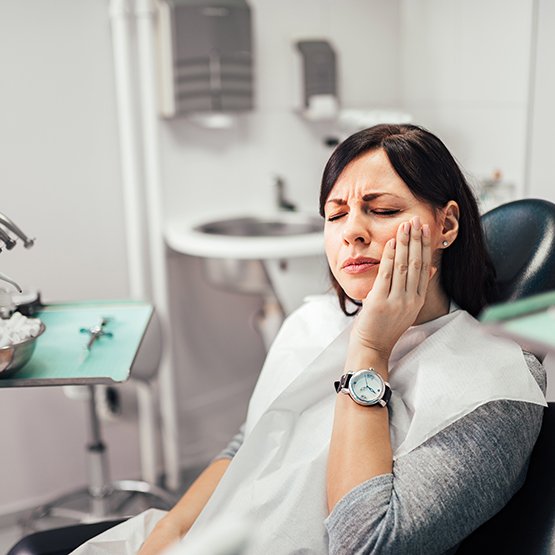 Woman with toothache sitting in dental chair