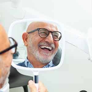 Man with black glasses smiling in reflection