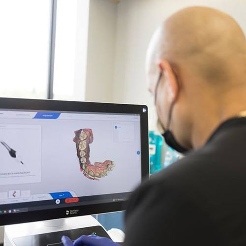 Dentist looking at render of teeth on computer monitor