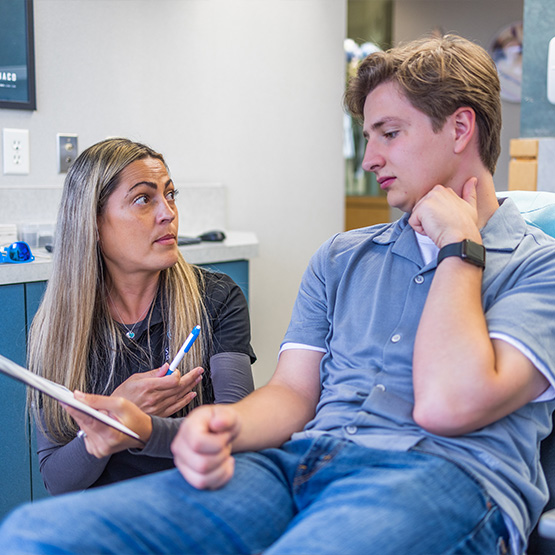 Teen patient and dentist holding Invisalign