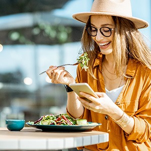 Woman with black glasses smiling while talking on phone
