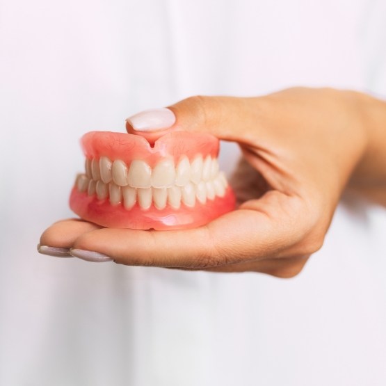 Close up of hands holding full dentures