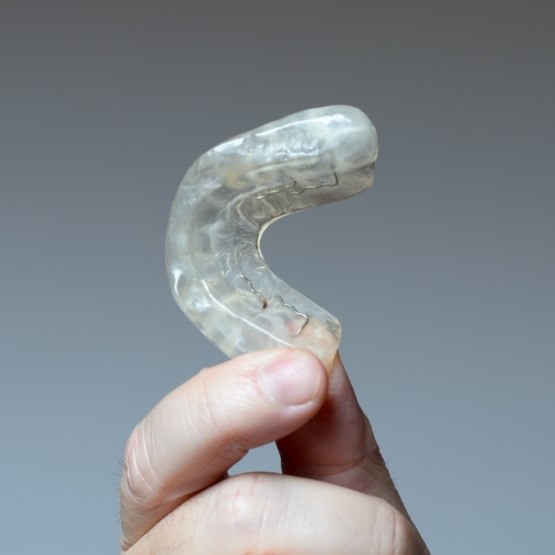 Fingers holding nightguard for bruxism